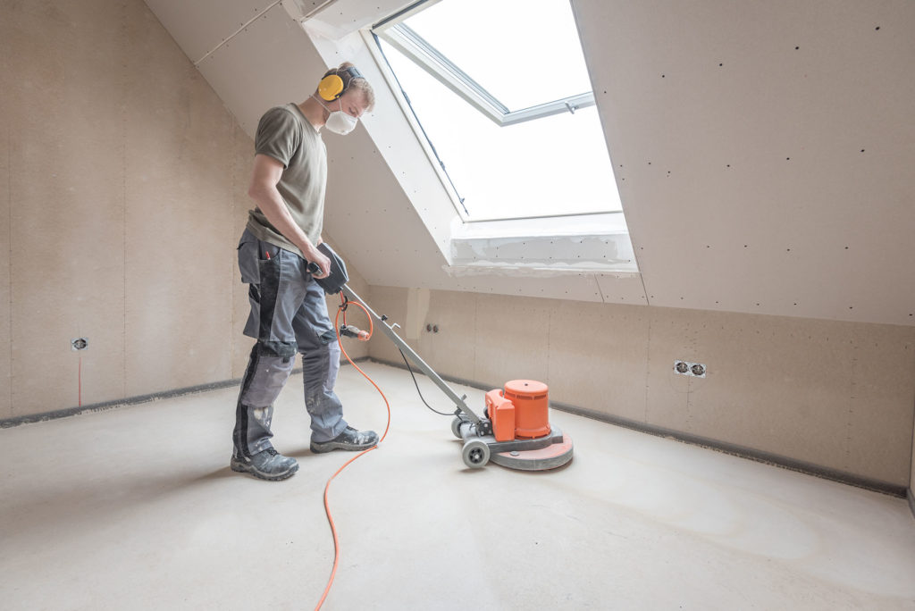 Handwerker schleift Estrichboden ab Innenausbau